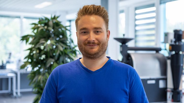 Portraitbild vor dem Kaffeeröster von Maximilian Staudt, Doktorand in der Fachrichtung Lebensmitteltechnik