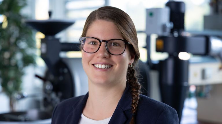 Portraitbild vor dem Kaffeeröster von Susanne Grimbach, Mitarbeiterin in der Fachrichtung Lebensmitteltechnik